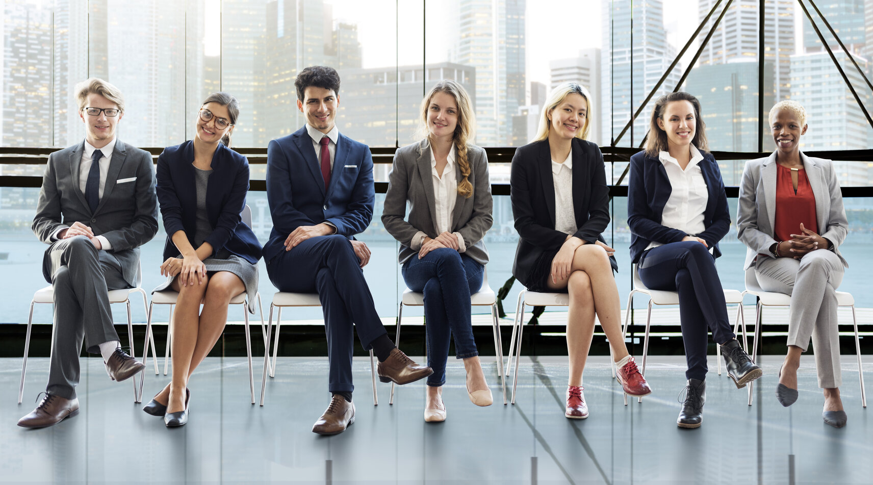 Professional PA interview attire for men and women: a woman in a tailored navy suit with a white blouse and a man in a classic gray suit with a blue tie, both accessorized with simple, polished details.